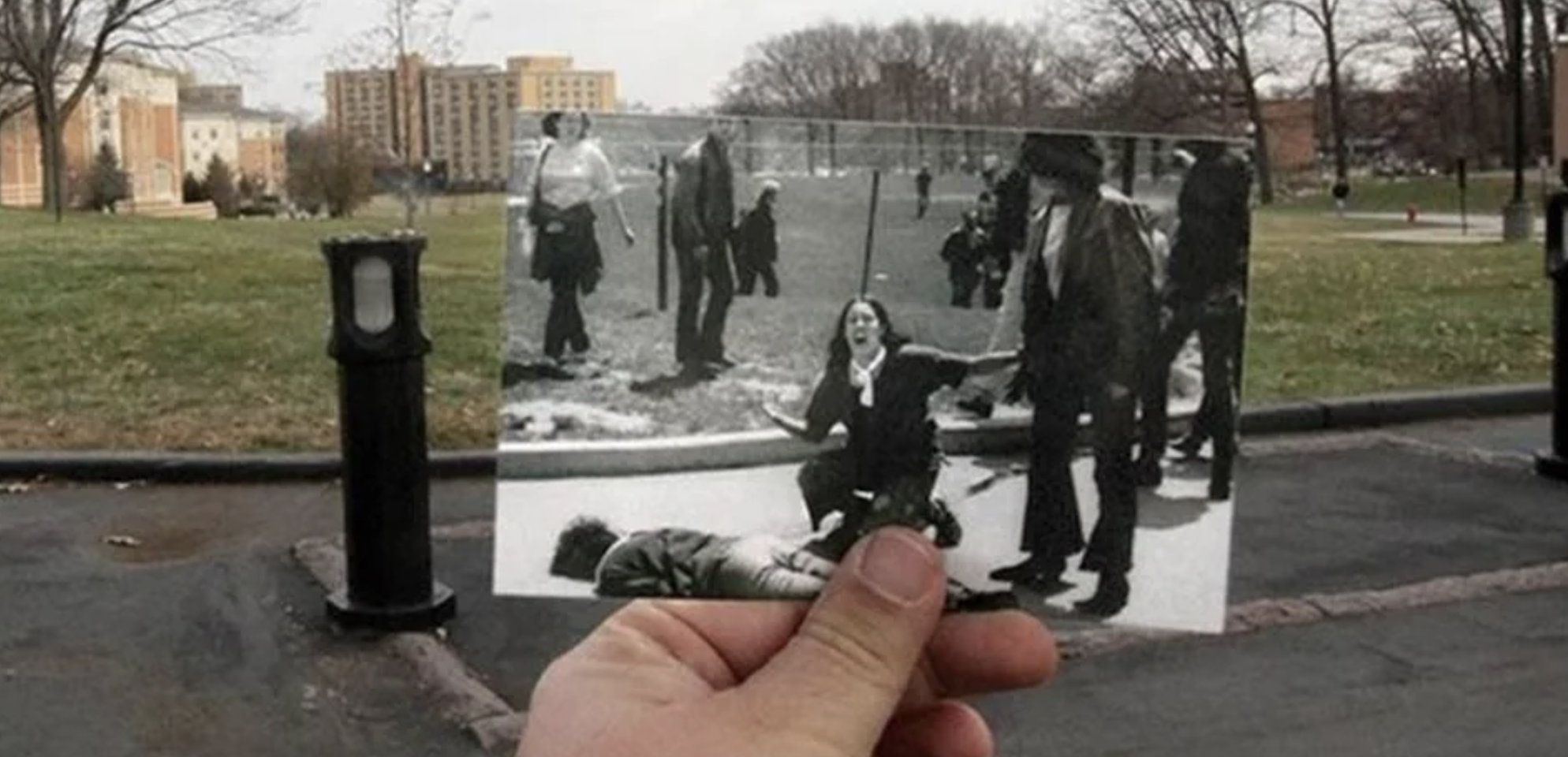 Alt text: A hand aligns the famous 1970 Kent State shooting photo—showing a distraught student kneeling over a fallen protester—against the same campus lawn today, contrasting the black‑and‑white tragedy with a quiet, color scene.